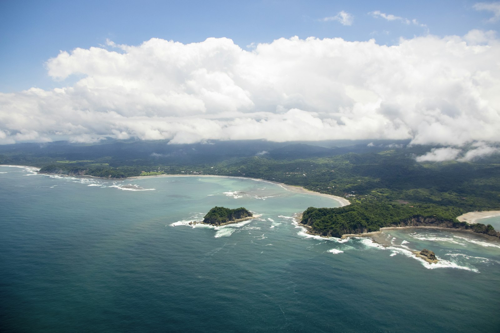 Aerial view of a green island surrounded by clear blue ocean water in Central America